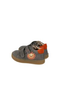 Zapatos de cuero gris con suela marrón, que cuentan con dos correas de velcro y un gráfico de un león en naranja y amarillo en el costado.