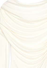 Top in tessuto crema drappeggiato con una consistenza morbida e liscia. Presenta dettagli arricciati lungo il colletto, creando una silhouette elegante.
