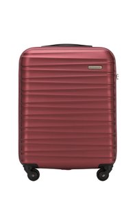 Valise rigide bordeaux avec une texture striée, équipée d'une poignée noire et de quatre roulettes pour la mobilité.