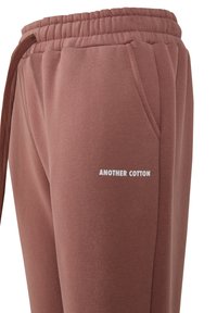 Pantalones de chándal de algodón en un color rosa apagado con cintura elástica y bolsillos laterales. Presenta un logo impreso en blanco: "ANOTHER COTTON."
