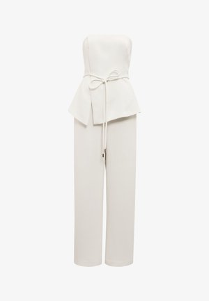 Biely overal bez ramienok so širokými nohavicami, asymetrickým peplum v páse a previazaným opaskom vpredu.