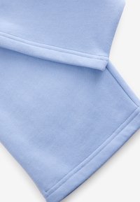 Lyseblå stof med en blød tekstur, der har rene kanter og sømme. Designet er enkelt og viser en glat, udekoreret overflade.