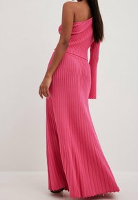Langes, rosa geripptes Kleid mit einseitigem Design und taillierter Passform, das in einen ausgestellten Saum übergeht. Aus strukturiertem, elastischem Material gefertigt.