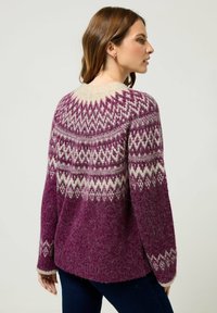 Übergroßer lila Strickpullover mit weißen geometrischen Mustern, strukturiertem Stoff, weiten Ärmeln und rundem Halsausschnitt.