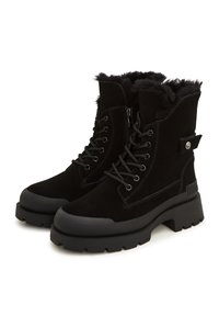 Botines de cuero negro con una suela negra gruesa, cordones en la parte delantera y un ribete de pelo sintético en el cuello. Incluyen una cremallera lateral y un diseño robusto.