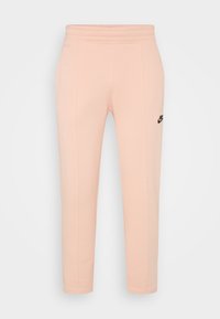 Světle růžové tepláky se zúženým střihem, vyrobené z měkké bavlněné směsi, s bočními švy a černým logem Nike na levém boku.