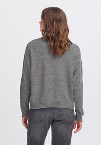 Pullover grigio lavorato a maglia con vestibilità rilassata, orlo e polsini a coste, caratterizzato da una texture morbida e spalle leggermente scese.