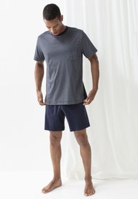 Marinblå randig kortärmad t-shirt med ficka, i kombination med marinblå shorts. Båda är gjorda av mjukt tyg och har en avslappnad passform.