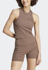 Brown ribbed athletic set featuring a sleeveless crop top and high-waisted shorts. Made of stretchy fabric with a fitted design.