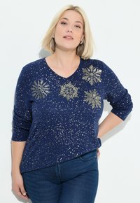Granatowy sweter z dekoltem w kształcie V i rękawami o długości trzech czwartych, zdobiony metalicznymi wzorami płatków śniegu oraz posiadający sznurki o drobnym wzorze.