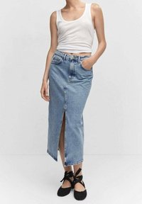 Vaaleansininen farkuhame, jossa on etuhiha, korkea vyötärö ja sivutaskut. Yhdistetty valkoiseen toppiin ja mustiin litteisiin kenkiin.