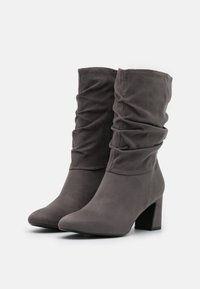 Stivaletti alla caviglia in suede grigio con un design morbido, punta tondeggiante e tacco a blocco di 5 cm. Texture arricciata unica sulla gamba.