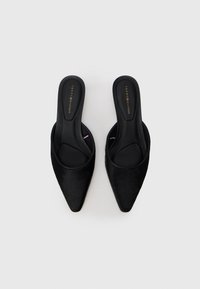 Schwarze, spitz zulaufende Slippers mit weichem, strukturiertem Obermaterial und glattem Fußbett. Mit einem dezenten, geprägten Logo auf der Innensohle.