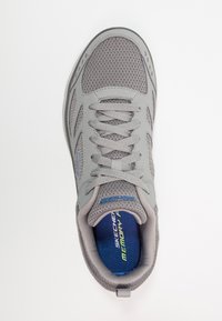 Grey athletic shoe with mesh upper, lace-up design, padded collar, and blue insole featuring "Memory Foam" text. Smooth rubber outsole.