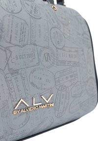 Borsa grigia con superficie texturizzata e motivo a timbro di viaggio in rilievo. Ferramenta dorata e dettaglio del marchio sul davanti.