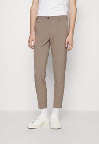 Chinos in tessuto marrone chiaro, slim fit con chiusura a bottone, dotati di tasche laterali e una finitura pulita. Abbinati a sneakers bianche.