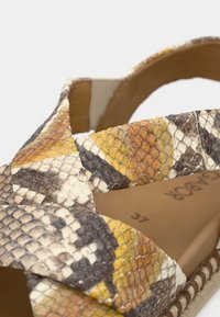 Πολύχρωμο σανδάλι με υφή, με σχέδιο σταυρωτού ιμάντα σε ψεύτικο δέρμα φιδιού με αποχρώσεις κίτρινου, καφέ και κρεμ.