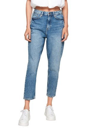Jeans en denim bleu clair avec une taille haute, coupe droite et détails déchirés. Portés avec des baskets blanches, mettant en valeur un look décontracté.