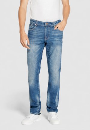 Jeans de mezclilla azul claro con un corte recto, que presentan un sutil desgaste y un diseño clásico de cinco bolsillos. Combinados con zapatillas blancas.