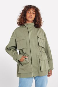 Veste olive avec un col haut, fermeture éclair sur le devant, plusieurs poches à rabat, taille cintrée et tissu léger. Design décontracté.