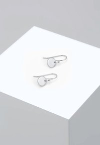 Pendientes de plata con un diseño de disco circular. Presentan una superficie lisa y un cierre de gancho. Estilo minimalista sobre un fondo claro.