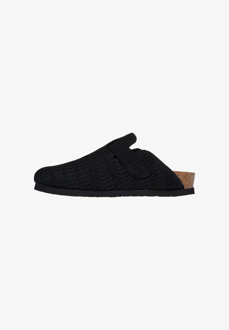 Chaussure noire en tricot à enfiler avec une surface texturée, dotée d'un accent en liège au niveau du talon et d'une fermeture à crochets et boucles. Semelle en caoutchouc plate.