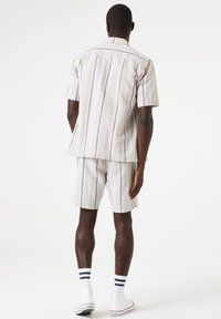 Korte mouwen overhemd met knoop en broekshorts set in lichtbeige met blauwe verticale strepen, gemaakt van gestructureerde stof. Inclusief een relaxte pasvorm en kraag.