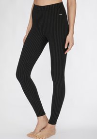 Zwarte leggings met verticale witte streepjes, gemaakt van rekbaar materiaal. Bevat een brede tailleband en een nauwsluitend ontwerp.