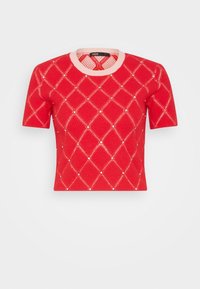 Top de punto rojo de manga corta con cuello rosa claro, patrón de diamantes y pequeños clavos plateados en las intersecciones sobre un fondo liso.