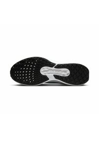 Suela de zapato con una superficie de goma negra texturizada; presenta una entresuela blanca y detalles del logotipo. El patrón incluye formas de diamante y hexágono.