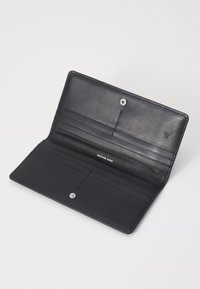 Portefeuille en cuir noir avec fermeture à bouton-pression, plusieurs emplacements pour cartes et une texture lisse. Équipé de quincaillerie en argent et de marquage gravé.