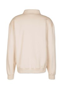Beige sweater with a polo collar, loose fit, and ribbed cuffs. Soft fabric with a smooth texture. Rear view highlights simplicity in design.