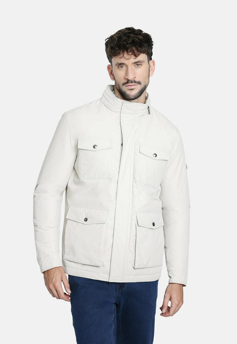Chaqueta aislante blanca con un alto cuello, dos bolsillos frontales con solapa y cierres a presión. Textura suave y un diseño moderno.