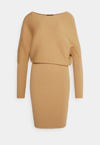 Stickad klänning i kamelfärg med en avslappnad, off-shoulder halsringning och långa ärmar. Strukturerad ribbad tyg, figurnära silhuett och knälängd.