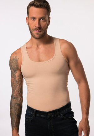 Beige tank top with a fitted design and wide shoulder straps, paired with dark denim jeans. Soft, stretchy fabric with a smooth texture.