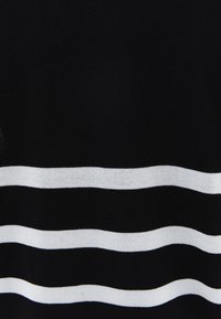Schwarzer Strickstoff mit horizontalen weißen Streifen. Die Streifen haben eine glatte Textur und variieren in der Breite über das Kleidungsstück.