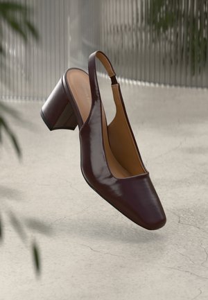Slingback-korkokenkä tumman viininpunaisesta patenttinaan, nelikulmaisella kärjellä, paksulla kannalla ja vaalealla sisäosalla, asetettuna tasaiselle taustalle.
