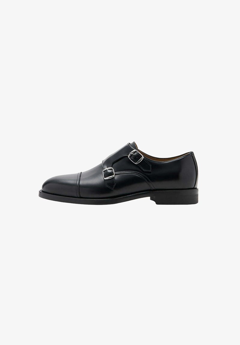Chaussure habillée en cuir noir avec double bride de moine, boucles argentées et talon bas, vue de côté extérieur sur fond blanc.