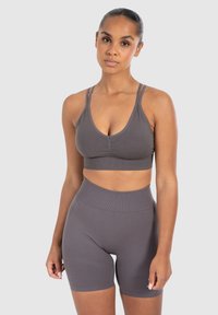 Grijze sportset bestaande uit een bralette met dunne banden en hoge shorts, gemaakt van ribbelmateriaal met een gladde textuur.