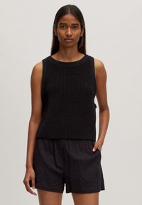 Zwarte mouwloze gebreide top met een ribbelstructuur, voorzien van een ronde halslijn en een comfortabele pasvorm, gecombineerd met zwarte textuurshorts.