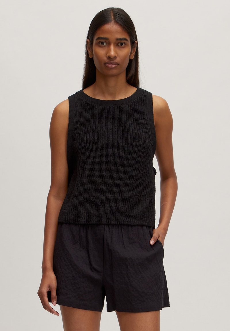 Zwarte mouwloze gebreide top met een ribbelstructuur, voorzien van een ronde halslijn en een comfortabele pasvorm, gecombineerd met zwarte textuurshorts.