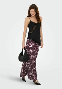 Camisole noire à dentelle, associée à une jupe maxi bordeaux à pois. Accessoirisée d'un sac à main noir et de ballerines noires pointues.