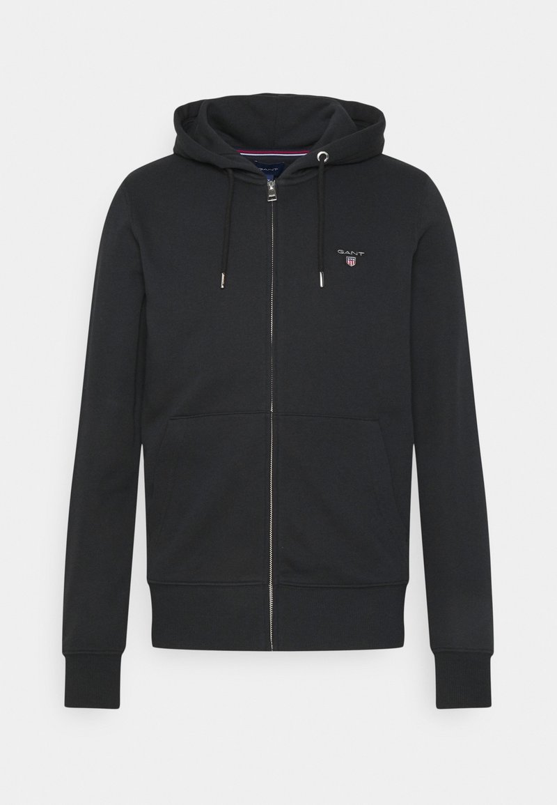 Sweat à capuche zippé noir avec poches avant, capuche à cordon, poignets côtelés et petit logo GANT sur la poitrine gauche.