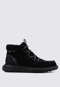Botas de ante negro con punta redondeada, costura texturizada y suela de goma con un patrón de olas; aseguradas con cordones de múltiples lazos.