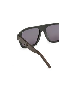 Černé sluneční brýle s tmavými skly, plastovými rámy a hnědými stranami s texturovaným vzorem. Aerodynamický tvar s ostrými hranami.