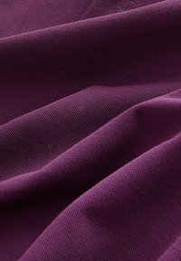 Țesătură texturată de culoare mov închis cu un model țesut, prezentând curbe și pliuri netede, evidențiind greutatea și structura materialului.