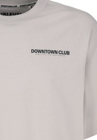 Light gray cotton t-shirt featuring a round neck, short sleeves, and a black printed logo on the chest with text "DOWNTOWN CLUB" and a slogan.