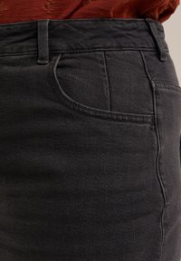 Jeans de mezclilla gris oscuro con un diseño clásico de cinco bolsillos, cinturilla estructurada y una textura sutil con detalles de costura visibles.