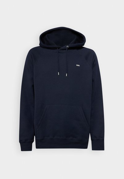 Mornarsko modra kapuca s kengurujskim žepom, vrvicami in minimalnim belem logotipu. Mešanica bombaža, mehka tekstura in rebrasti manšeti.