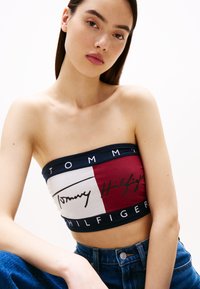 Tommy Hilfiger strapless top met rood, wit en blauwe kleurvlakken, met de merknaam en het logo prominent weergegeven in zwarte tekst.